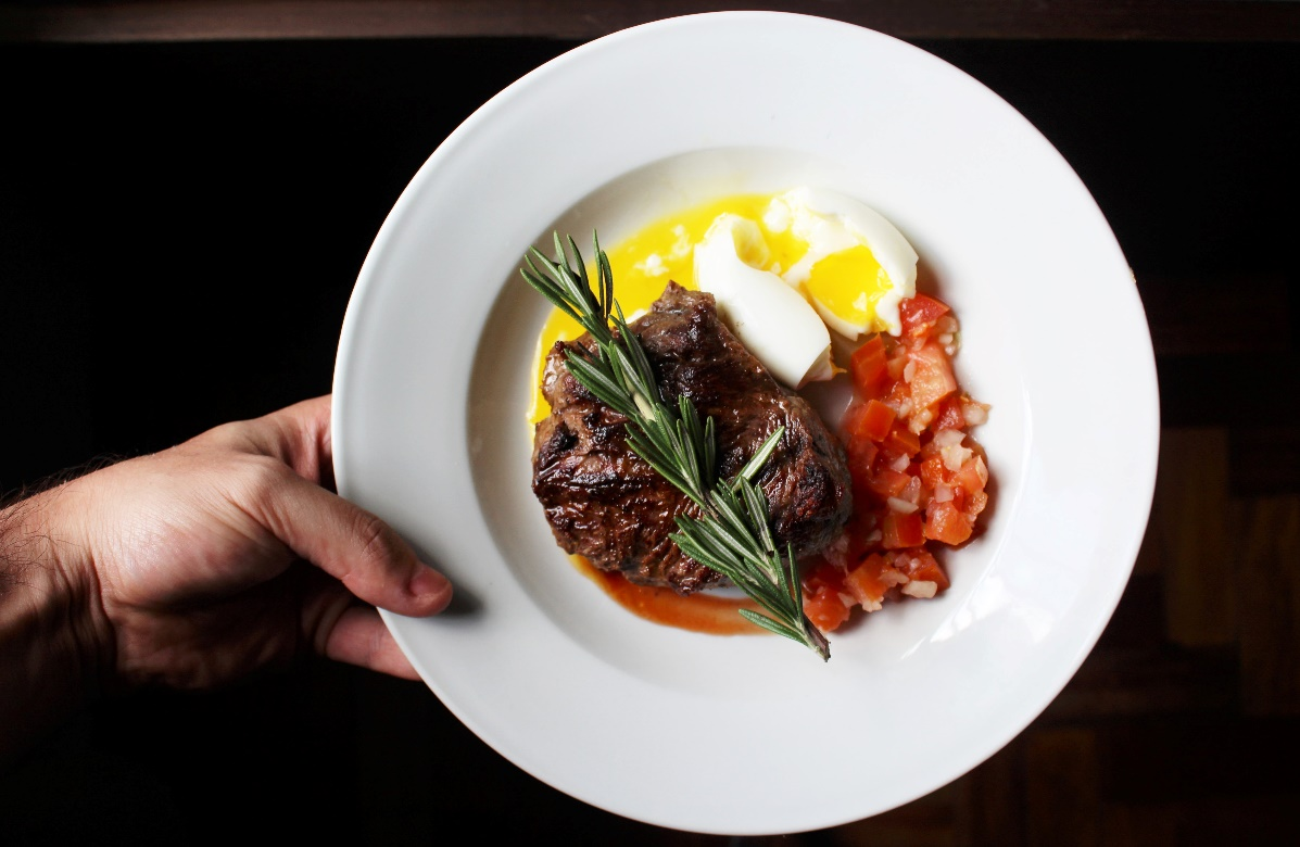 A person holding a white plate with food