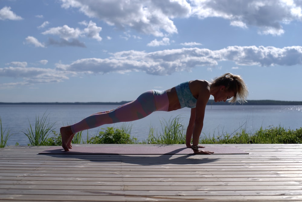 A Woman Performing Yoga on Her Hands and Toes by a Body of Water