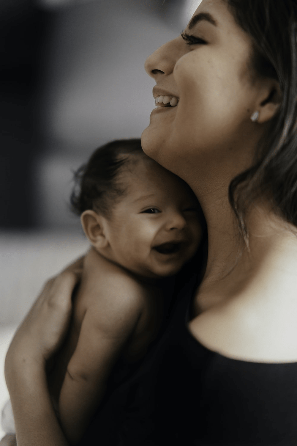 A Visibly Happy Woman Holds a Smiling Newborn Baby Close to Her Chest