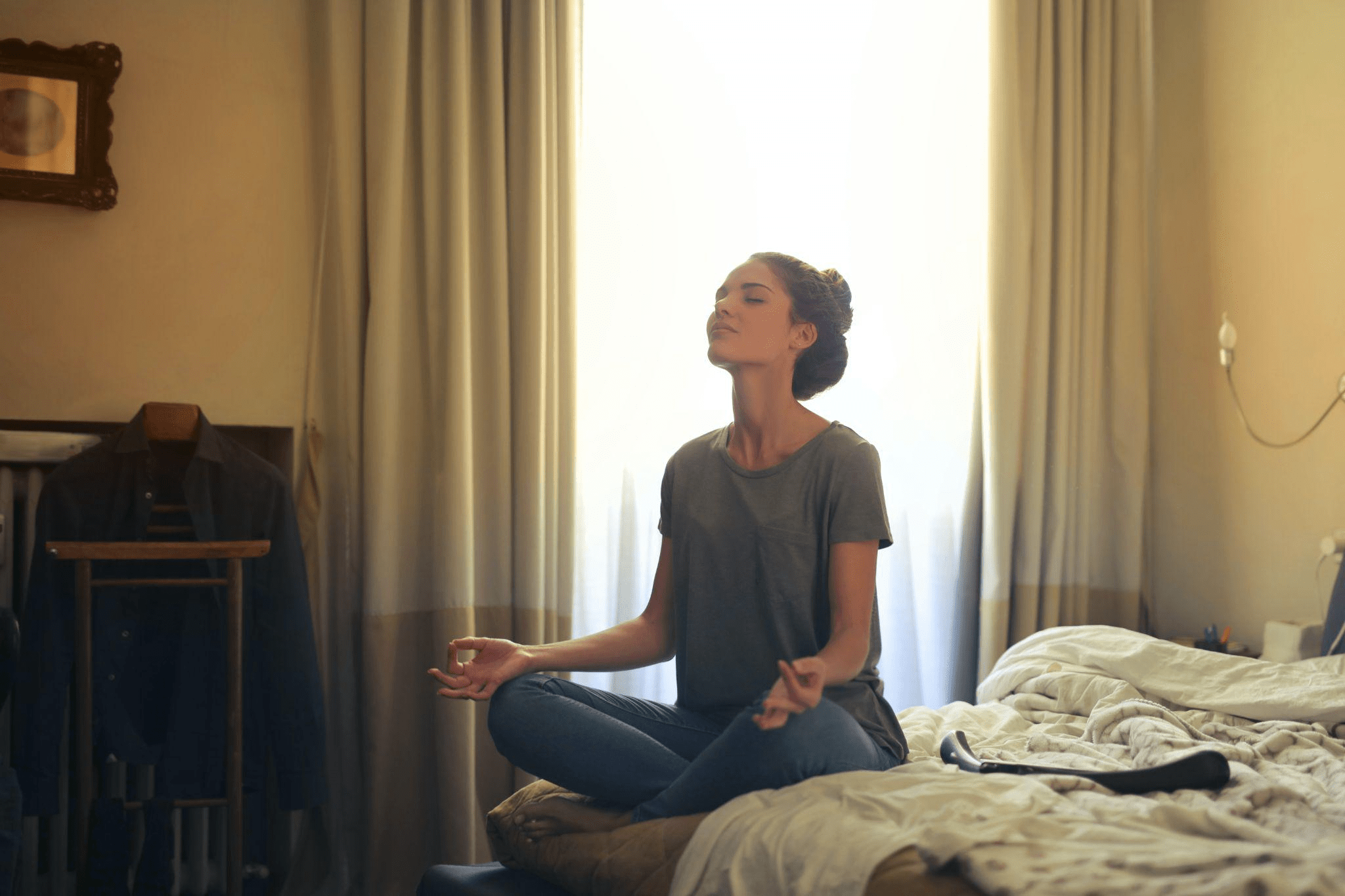 A woman practicing mindfulness meditation in her bedroom