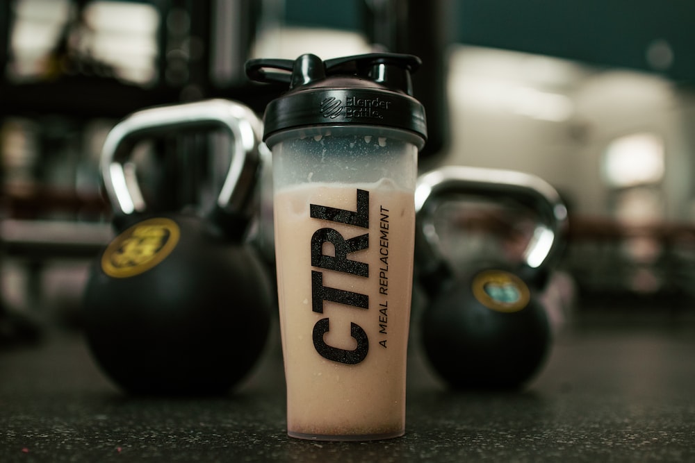 A glass of protein shake glass and dumbbells