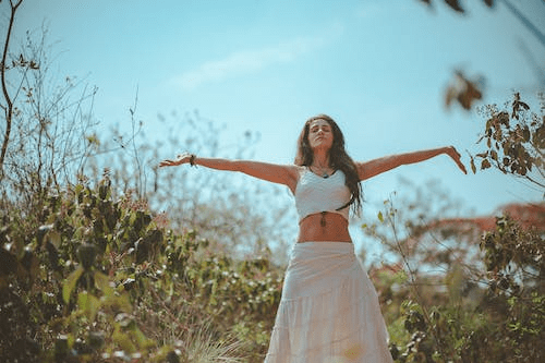 a woman standing with her arms open in a field