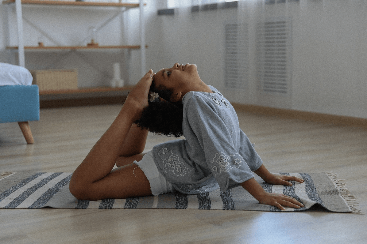  a girl practicing king pigeon pose on the rug