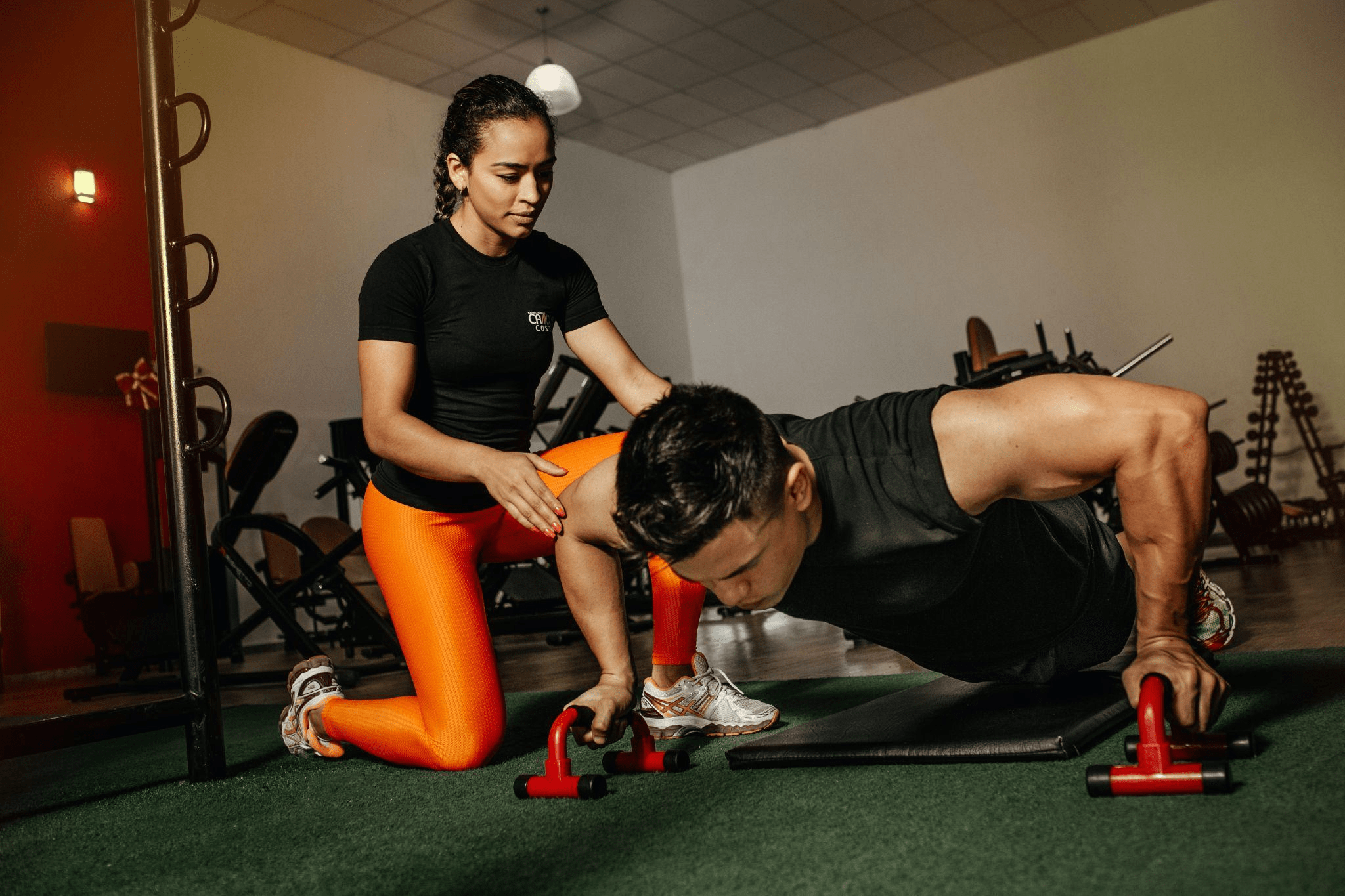 A woman helping a man during pushups